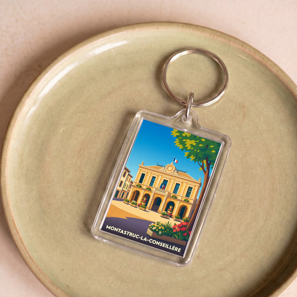 Porte-clés souvenir de la ville de Montastruc-la-Conseillère avec une illustration stylisée de sa mairie.