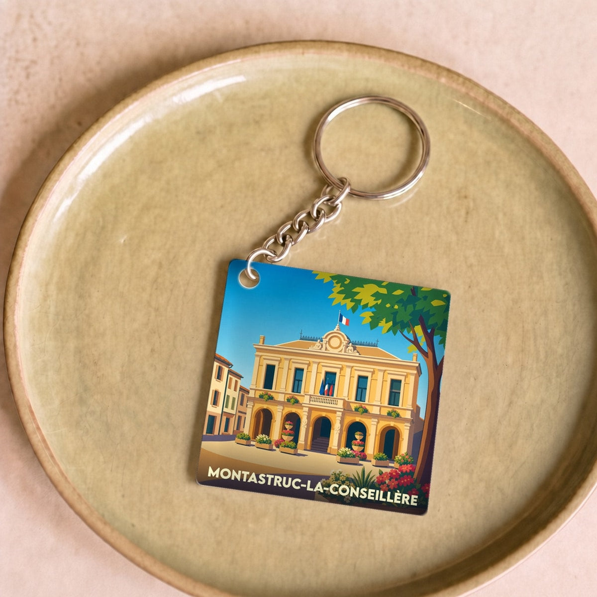 Porte-clés souvenir de la ville de Montastruc-la-Conseillère avec une illustration stylisée de sa mairie.