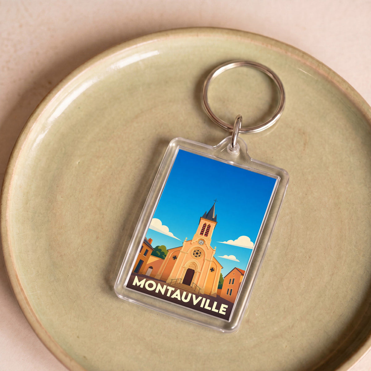 Porte-clés souvenir de la ville de Montauville avec une illustration stylisée de son église.