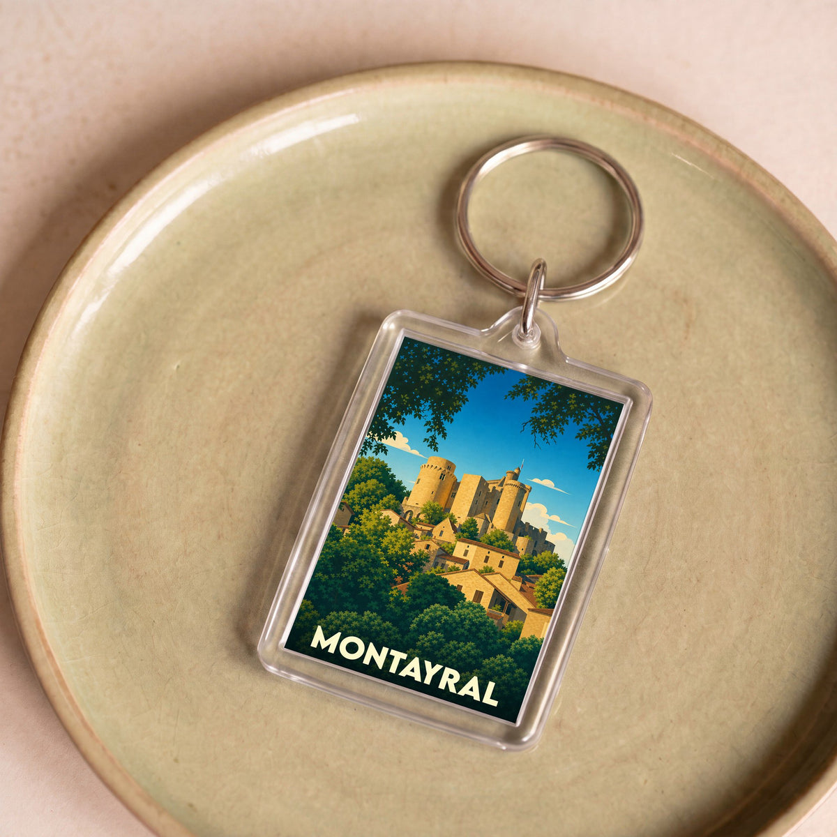 Porte-clés souvenir de la ville de Montayral avec une illustration stylisée de son château.