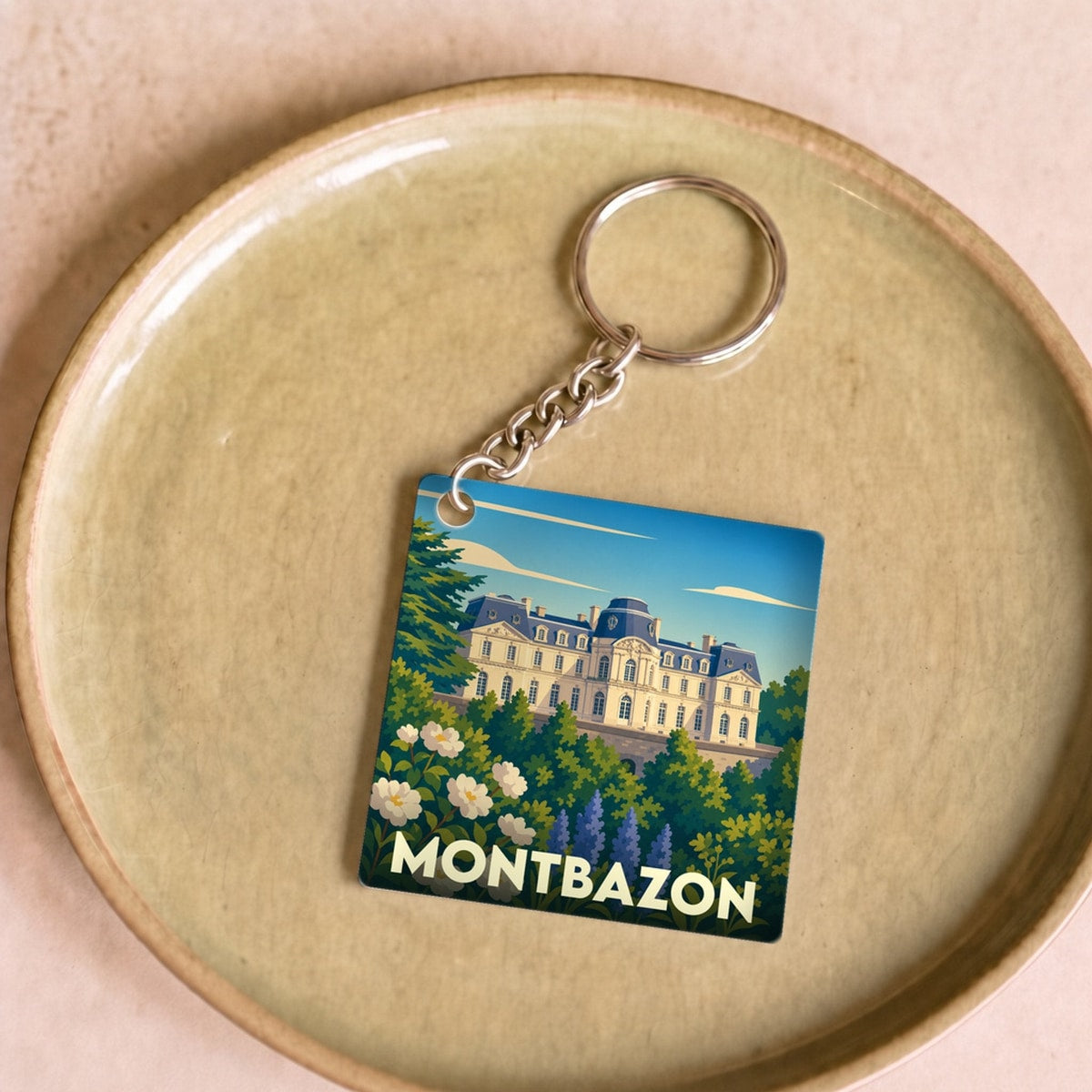 Porte-clés souvenir de la ville de Montbazon avec une illustration stylisée d'un château entouré de fleurs.