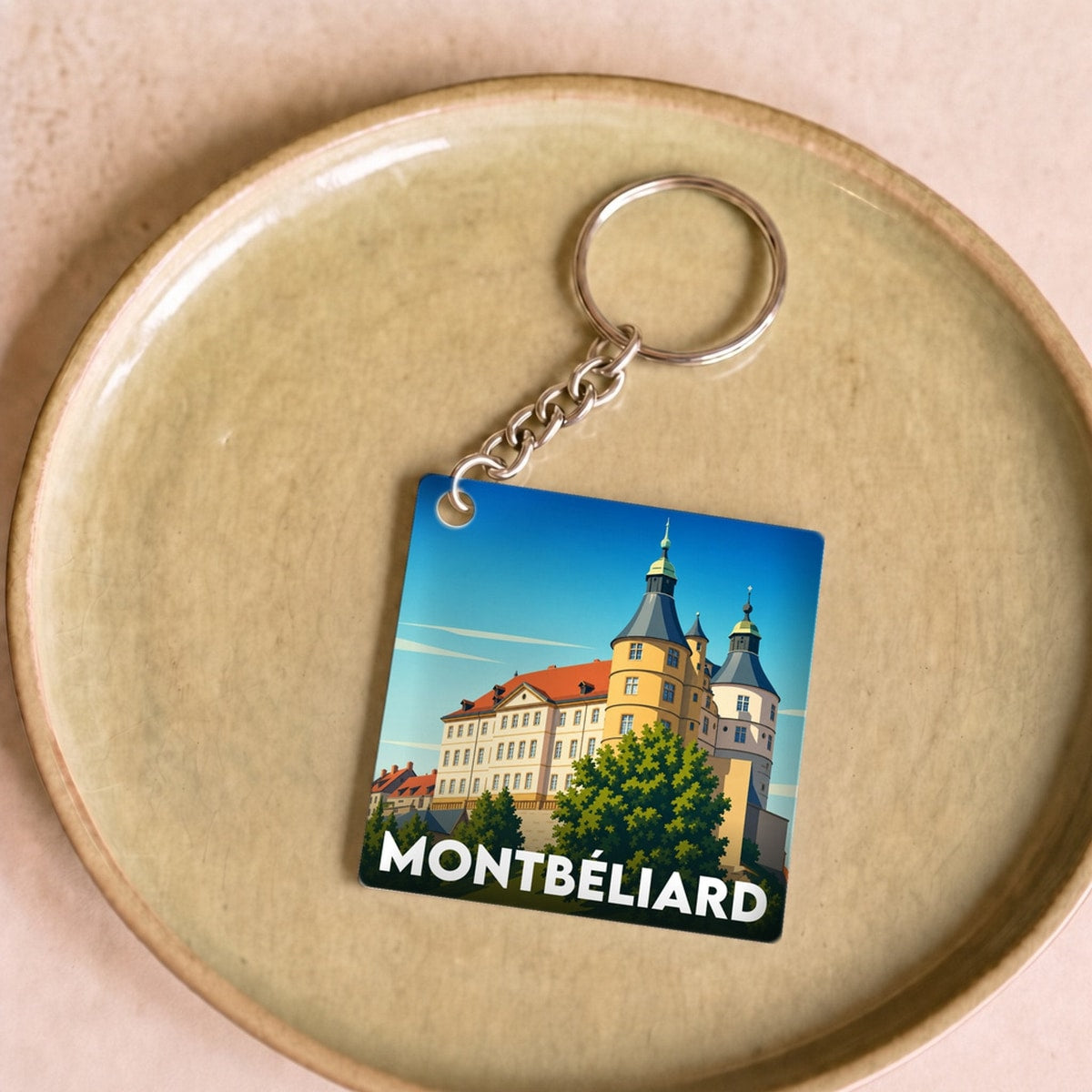 Porte-clés souvenir de la ville de Montbéliard avec une illustration stylisée.