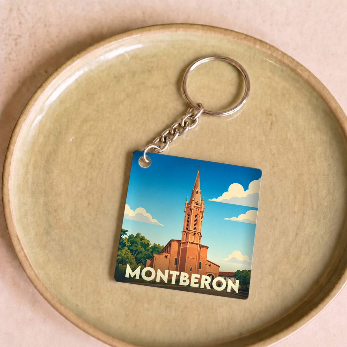 Porte-clés souvenir de la ville de Montberon avec une illustration stylisée de son église.