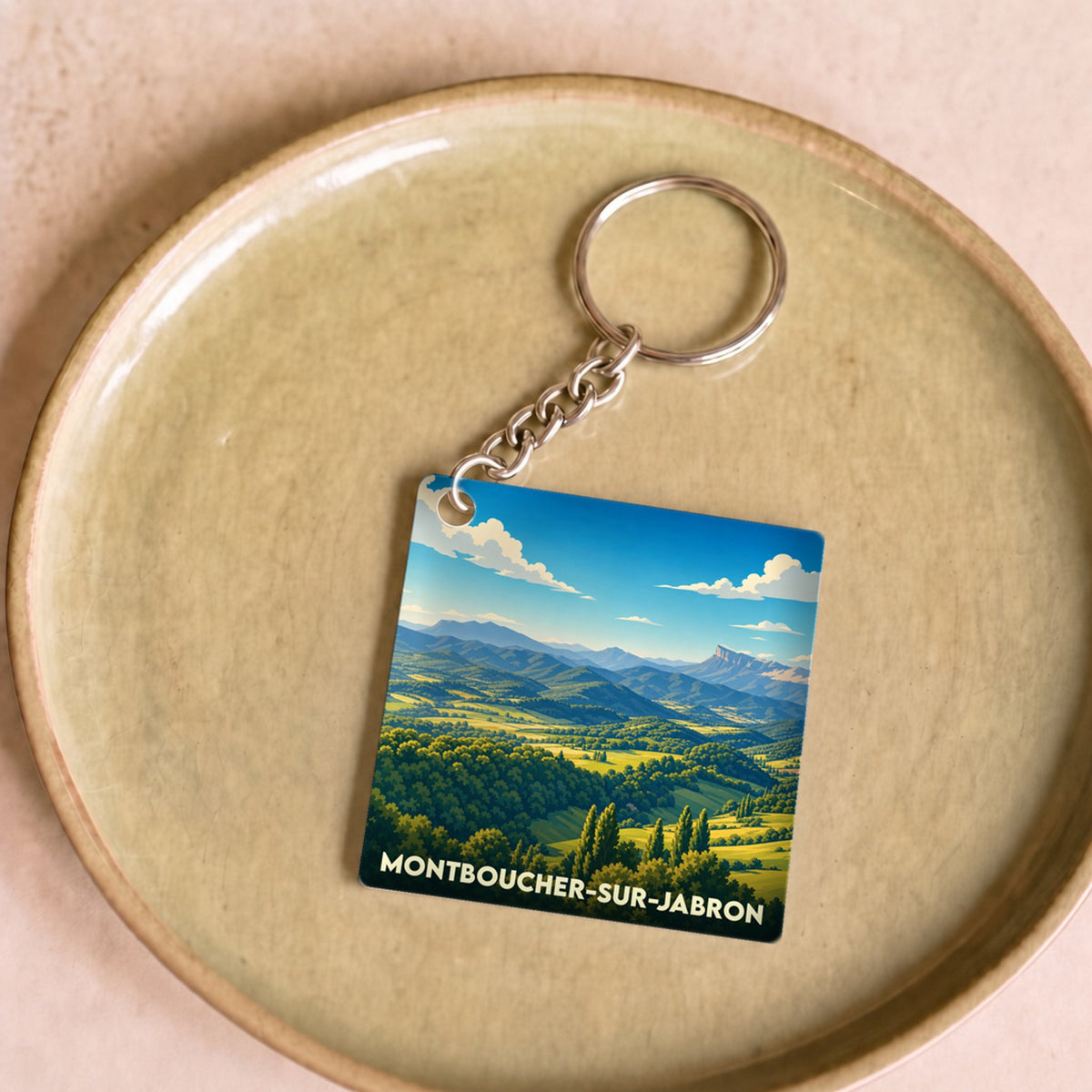 Porte-clés souvenir de la ville de Montboucher-sur-Jabron avec une illustration stylisée de paysages vallonnés.