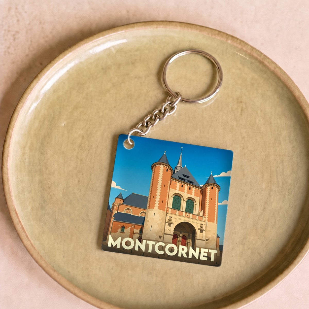 Porte-clés souvenir de la ville de Montcornet avec une illustration stylisée de son église fortifiée.