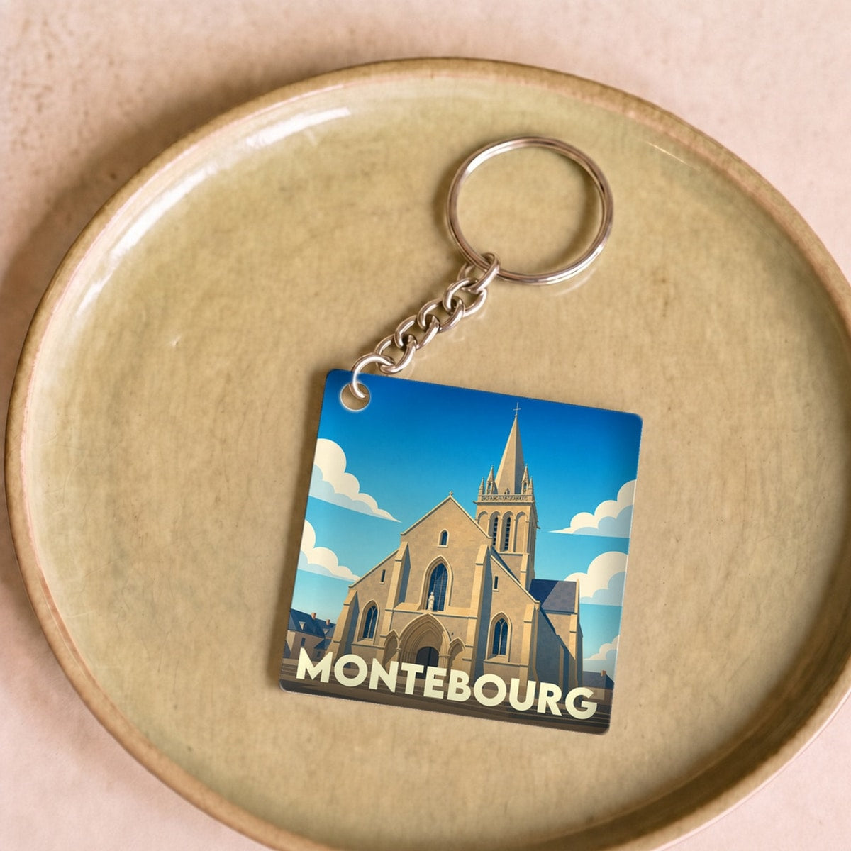 Porte-clés souvenir de la ville de Montebourg avec une illustration stylisée de son église.