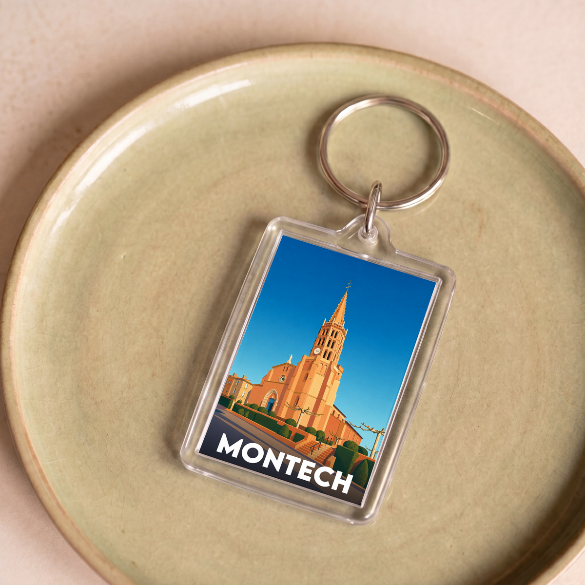Porte-clés souvenir de la ville de Montech avec une illustration stylisée de son église.