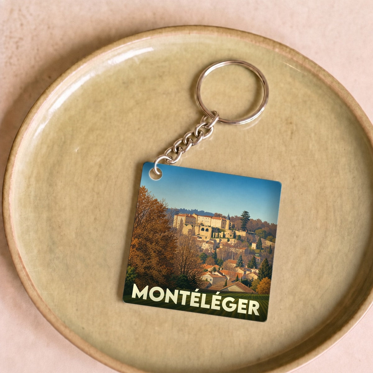 Porte-clés souvenir de la ville de Montéléger avec une illustration stylisée de son paysage urbain.