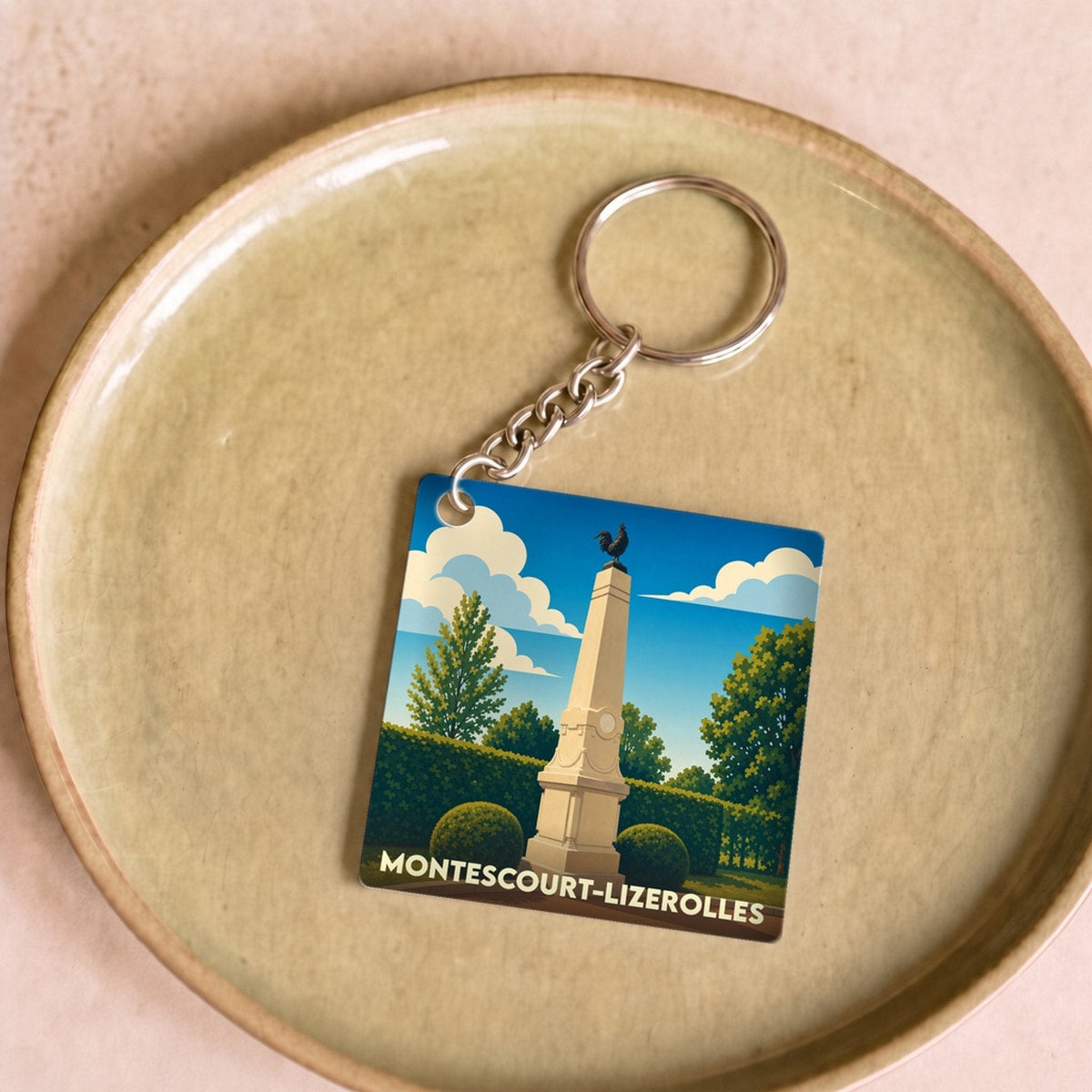 Porte-clés souvenir de la ville de Montescourt-Lizerolles avec une illustration stylisée de son monument aux morts.