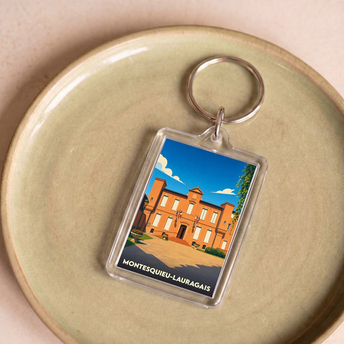 Porte-clés souvenir de la ville de Montesquieu-Lauragais avec une illustration stylisée de sa mairie.