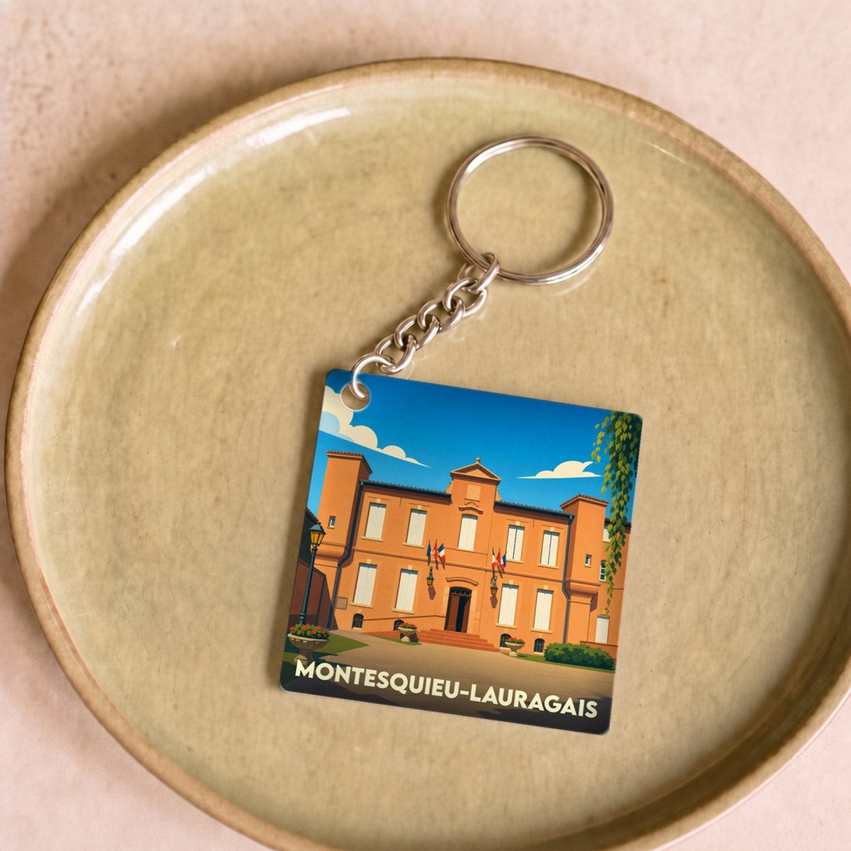 Porte-clés souvenir de la ville de Montesquieu-Lauragais avec une illustration stylisée de sa mairie.