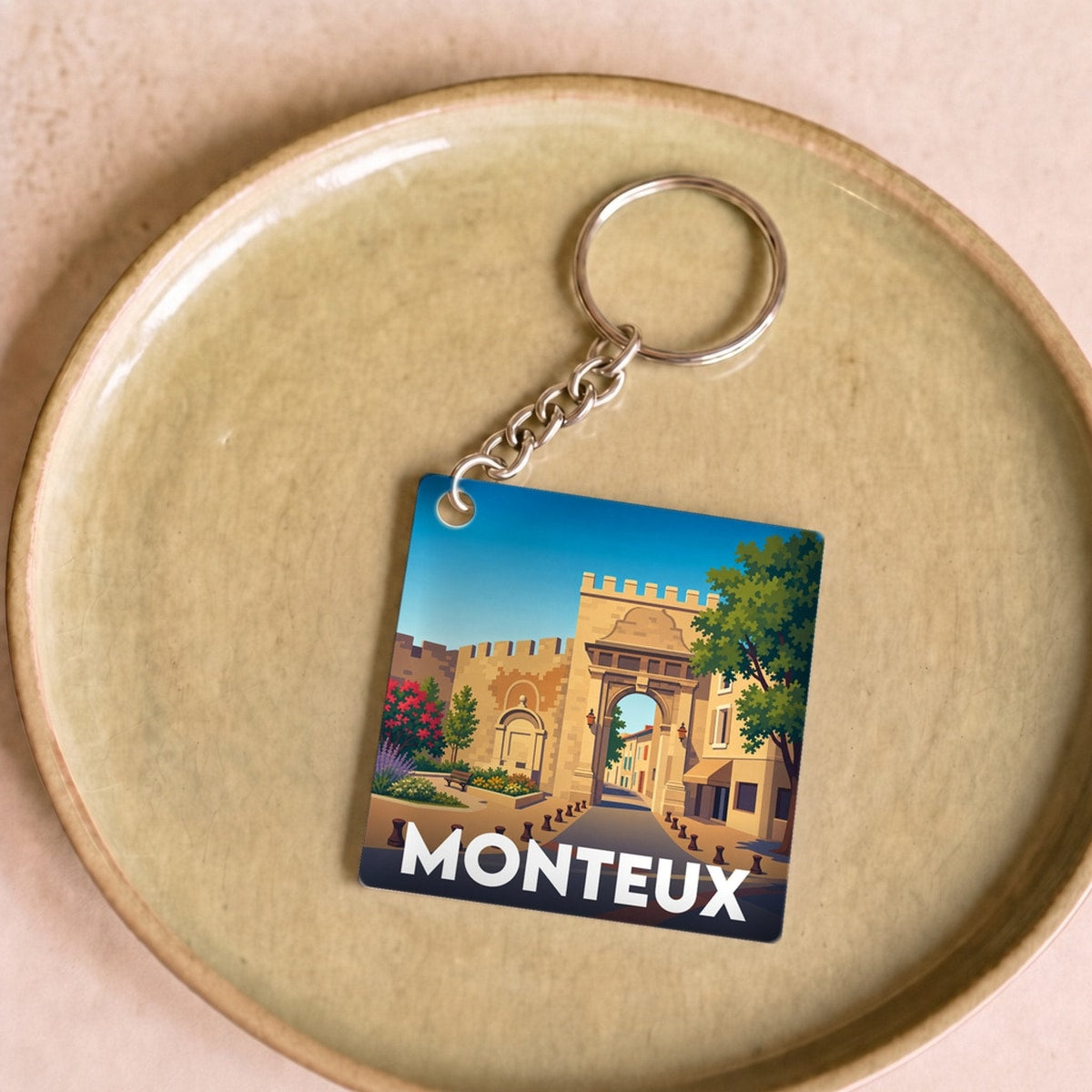 Porte-clés souvenir de la ville de Monteux avec une illustration stylisée.