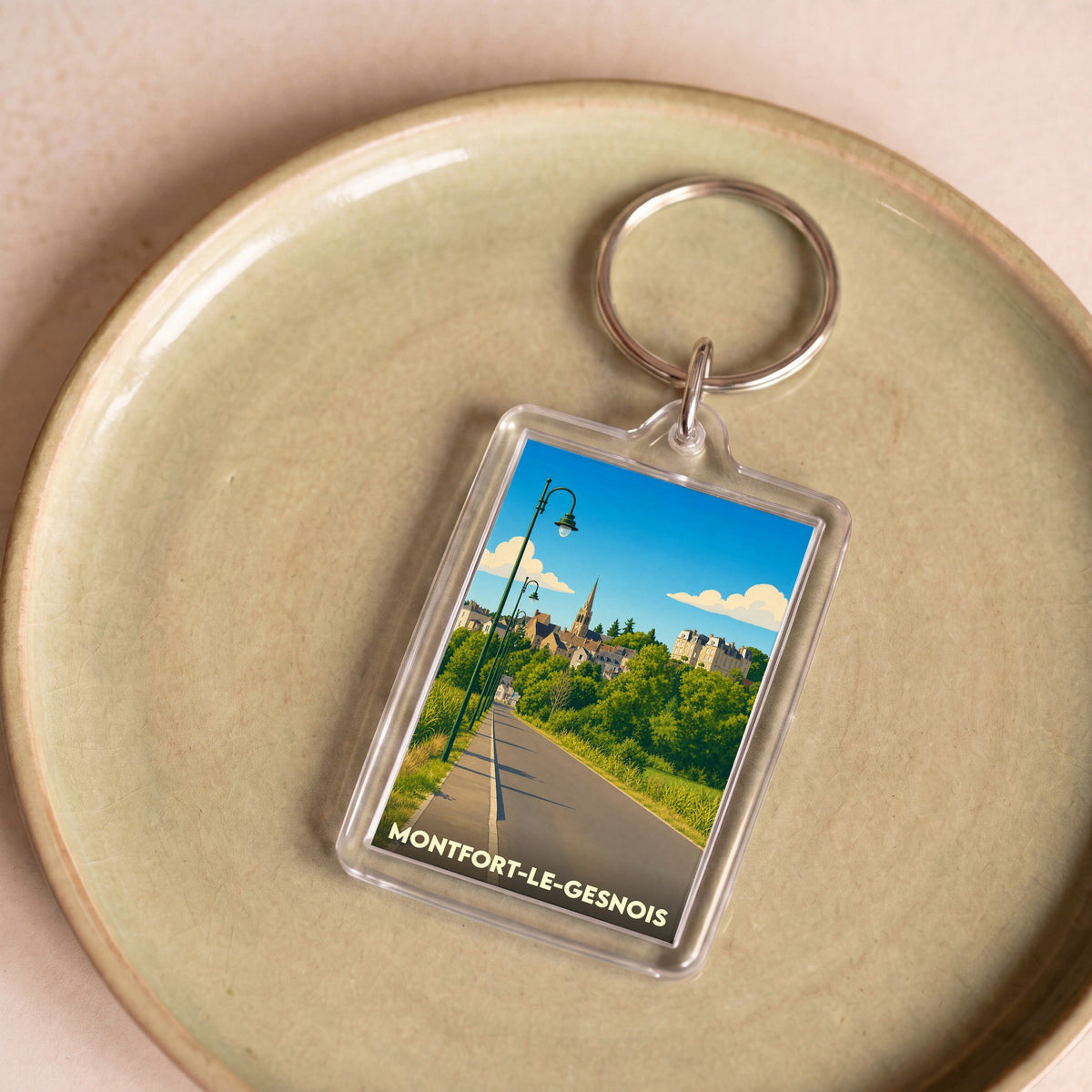 Porte-clés souvenir de la ville de Montfort-le-Gesnois avec une illustration stylisée.