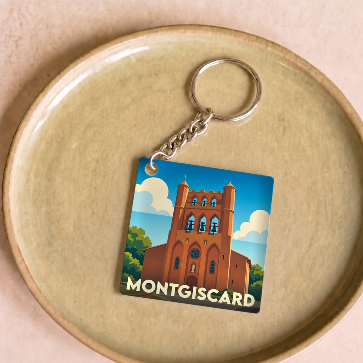 Porte-clés souvenir de la ville de Montgiscard avec une illustration stylisée de son église.