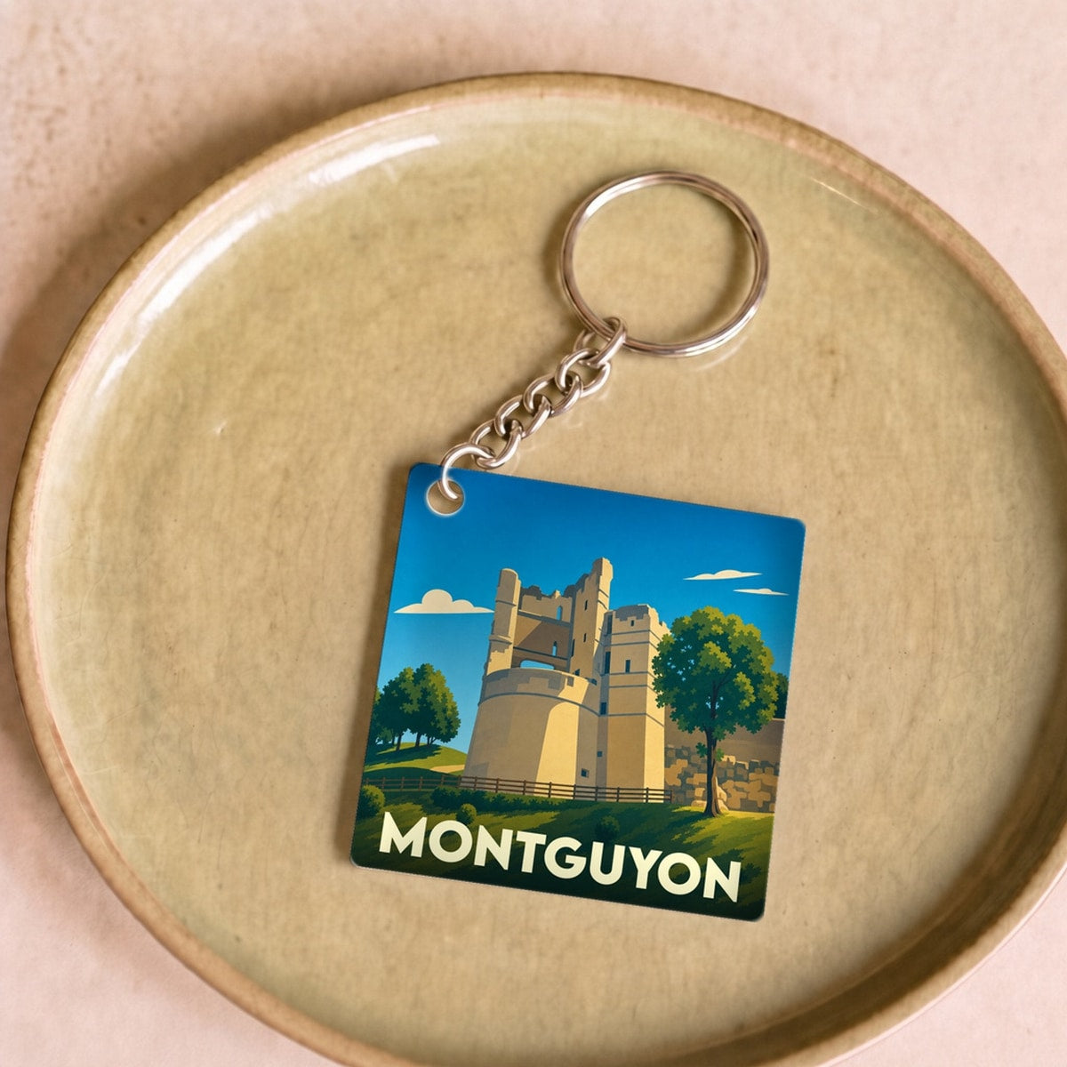 Porte-clés souvenir de la ville de Montguyon avec une illustration stylisée de son château.