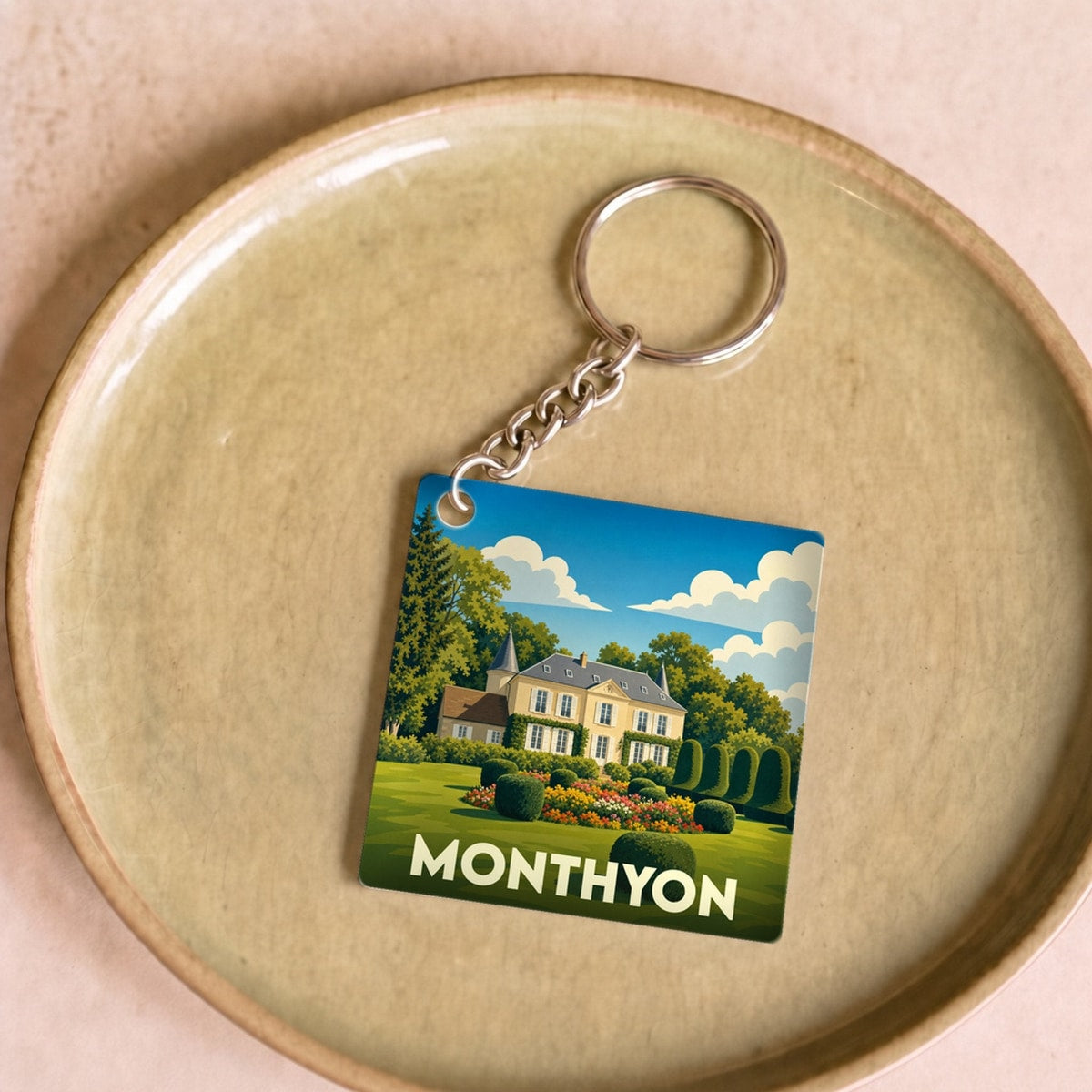 Porte-clés souvenir de la ville de Monthyon avec une illustration stylisée d'un domaine fleuri.