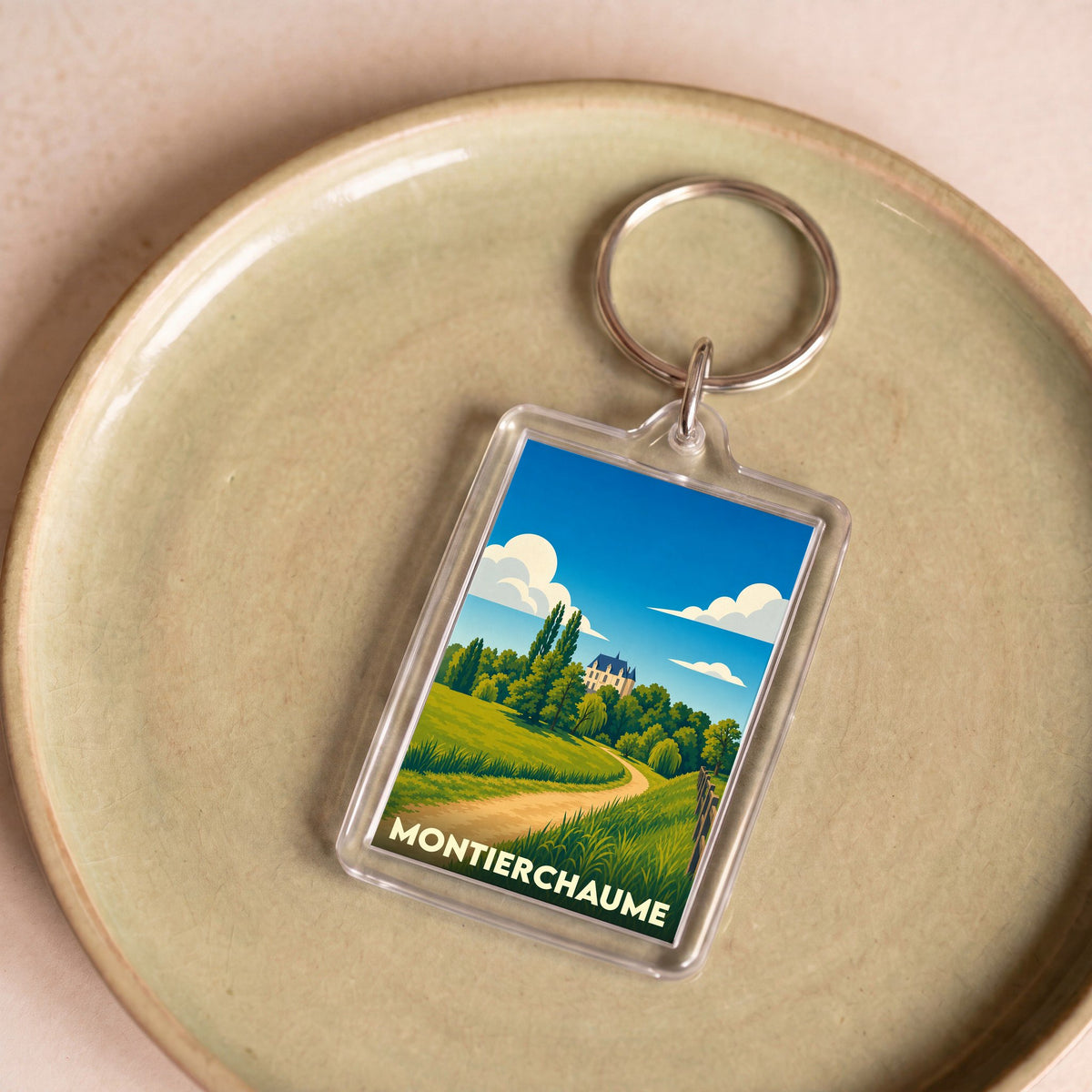 Porte-clés souvenir de la ville de Montierchaume avec une illustration stylisée d'un paysage de campagne.