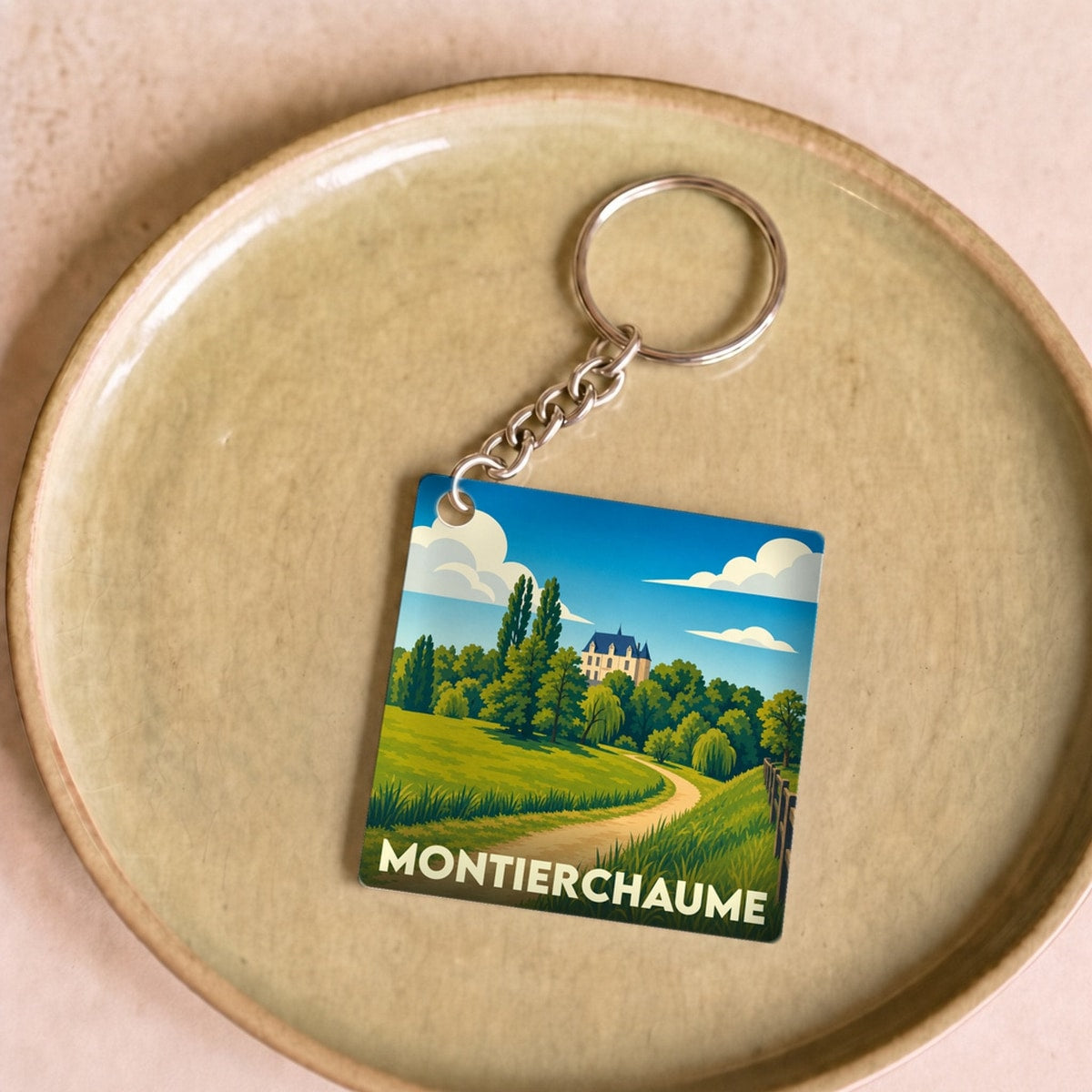Porte-clés souvenir de la ville de Montierchaume avec une illustration stylisée d'un paysage de campagne.