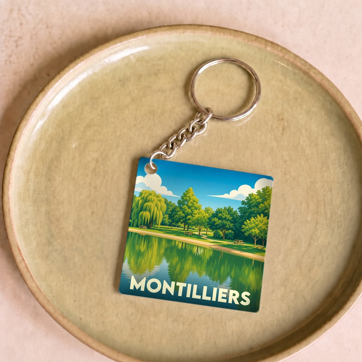 Porte-clés souvenir de la ville de Montilliers avec une illustration stylisée de son plan d'eau.
