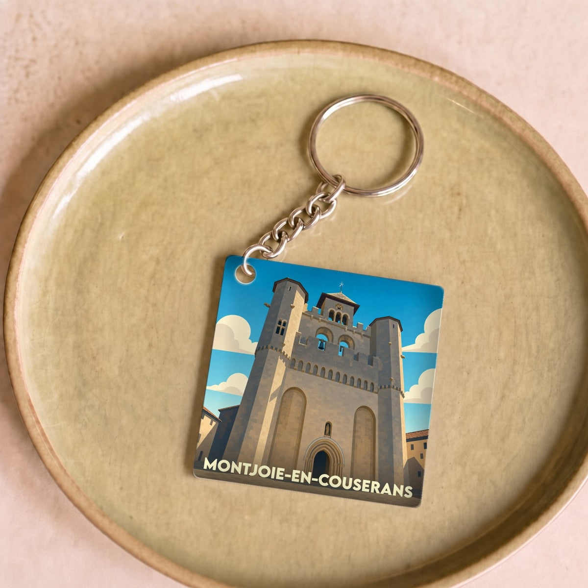 Porte-clés souvenir de la ville de Montjoie-en-Couserans avec une illustration stylisée de son église fortifiée.