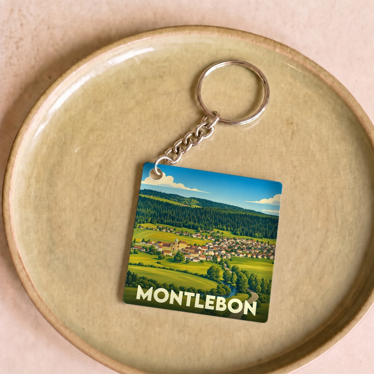 Porte-clés souvenir de la ville de Montlebon avec une illustration paysagère stylisée.