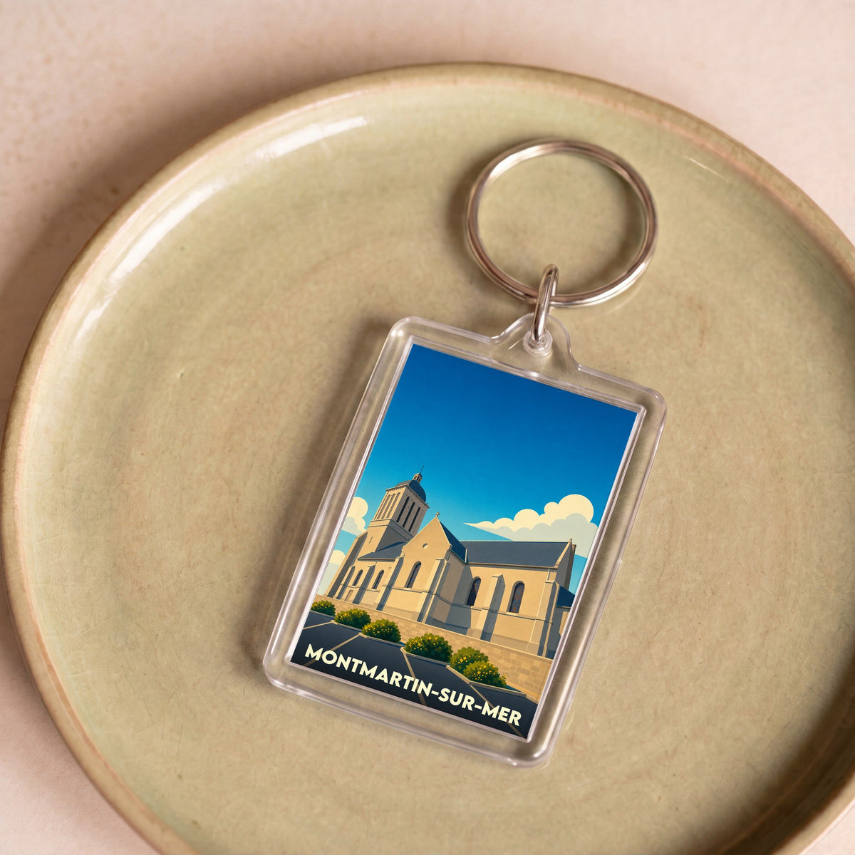 Porte-clés souvenir de la ville de Montmartin-sur-Mer avec une illustration stylisée de son église.