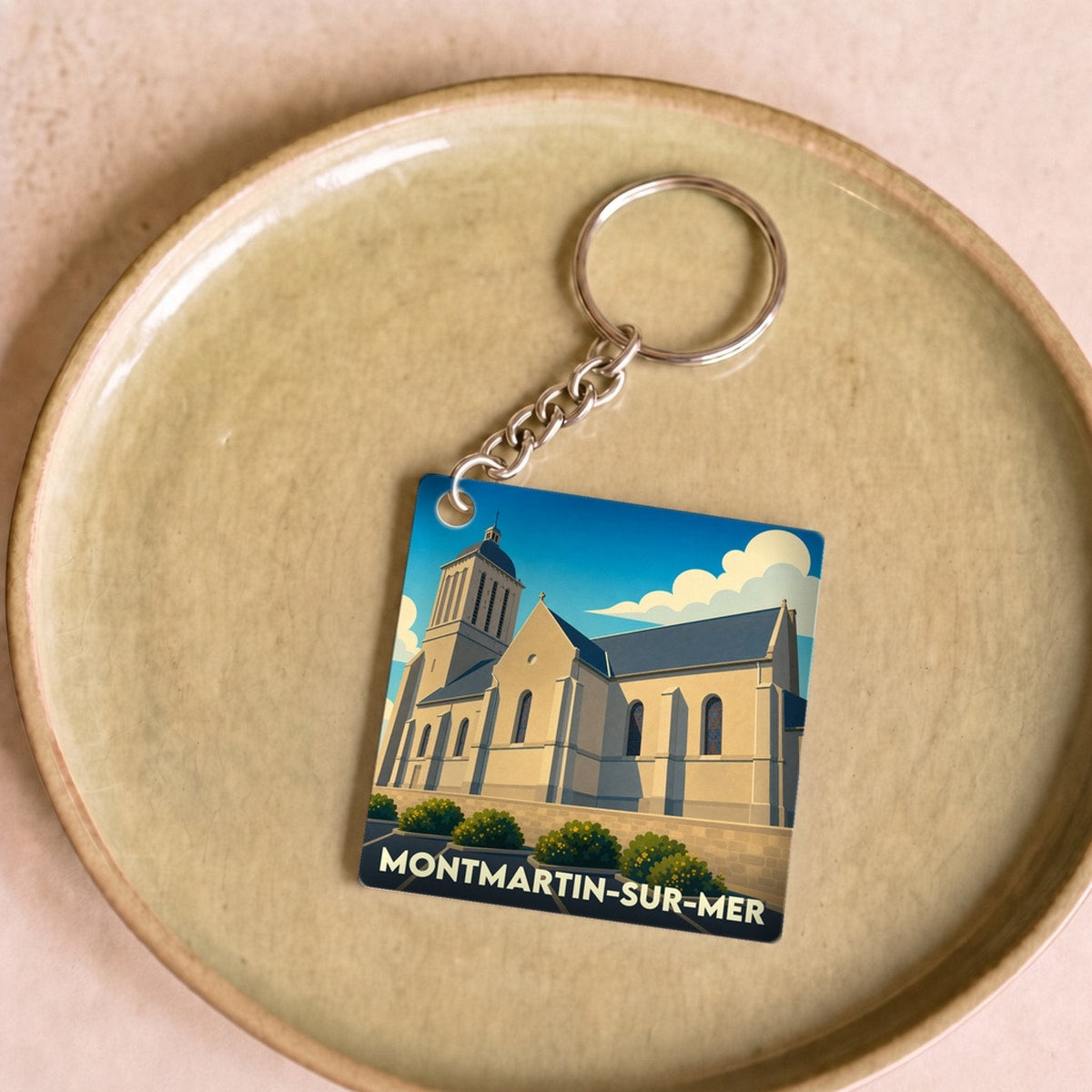 Porte-clés souvenir de la ville de Montmartin-sur-Mer avec une illustration stylisée de son église.