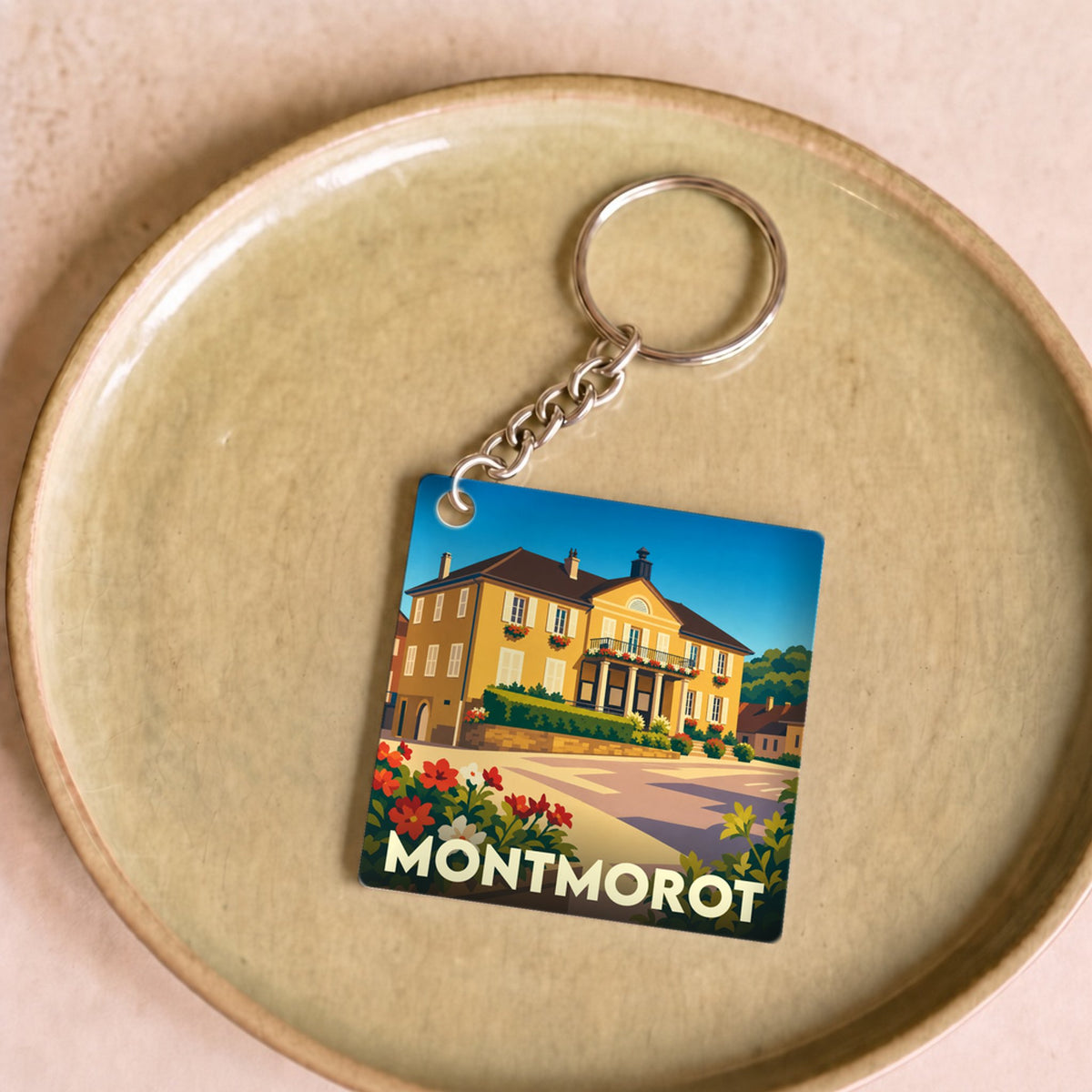 Porte-clés souvenir de la ville de Montmorot avec une illustration stylisée d'un bâtiment historique.