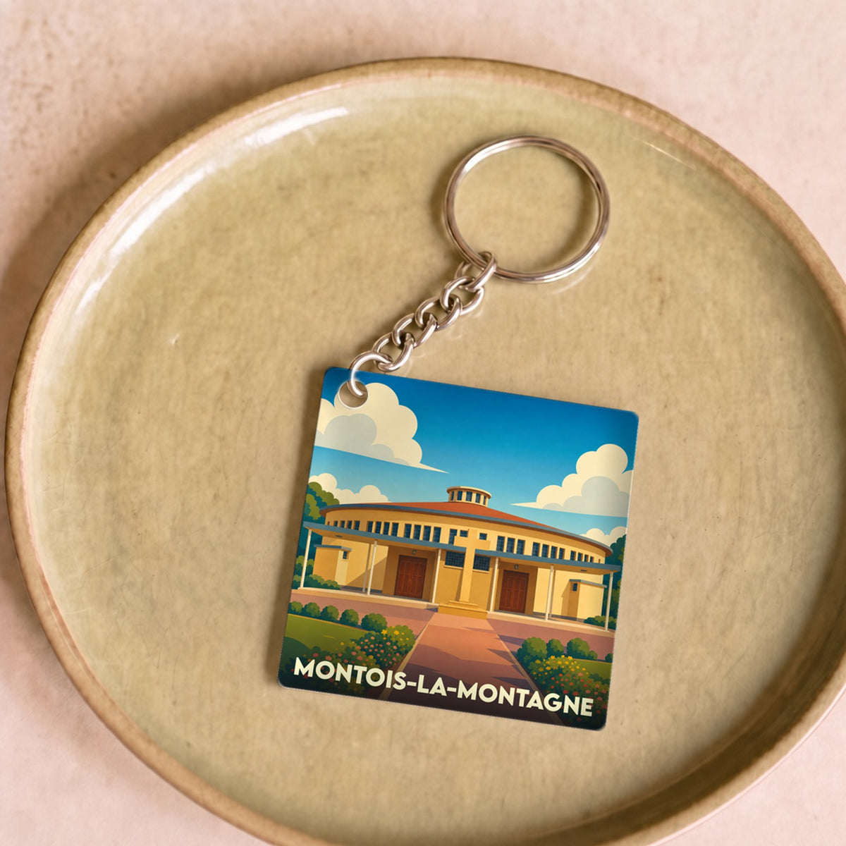 Porte-clés souvenir de la ville de Montois-la-Montagne avec une illustration stylisée d'un bâtiment circulaire.
