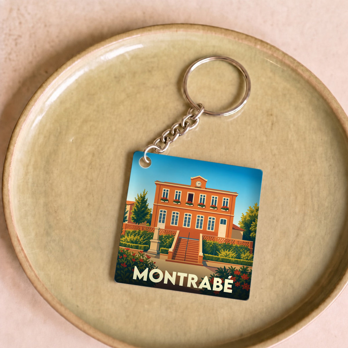 Porte-clés souvenir de la ville de Montrabé avec une illustration stylisée de sa mairie.