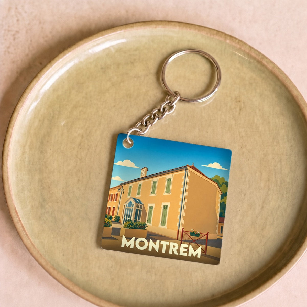 Porte-clés souvenir de la ville de Montrem avec une illustration stylisée d'un bâtiment emblématique.