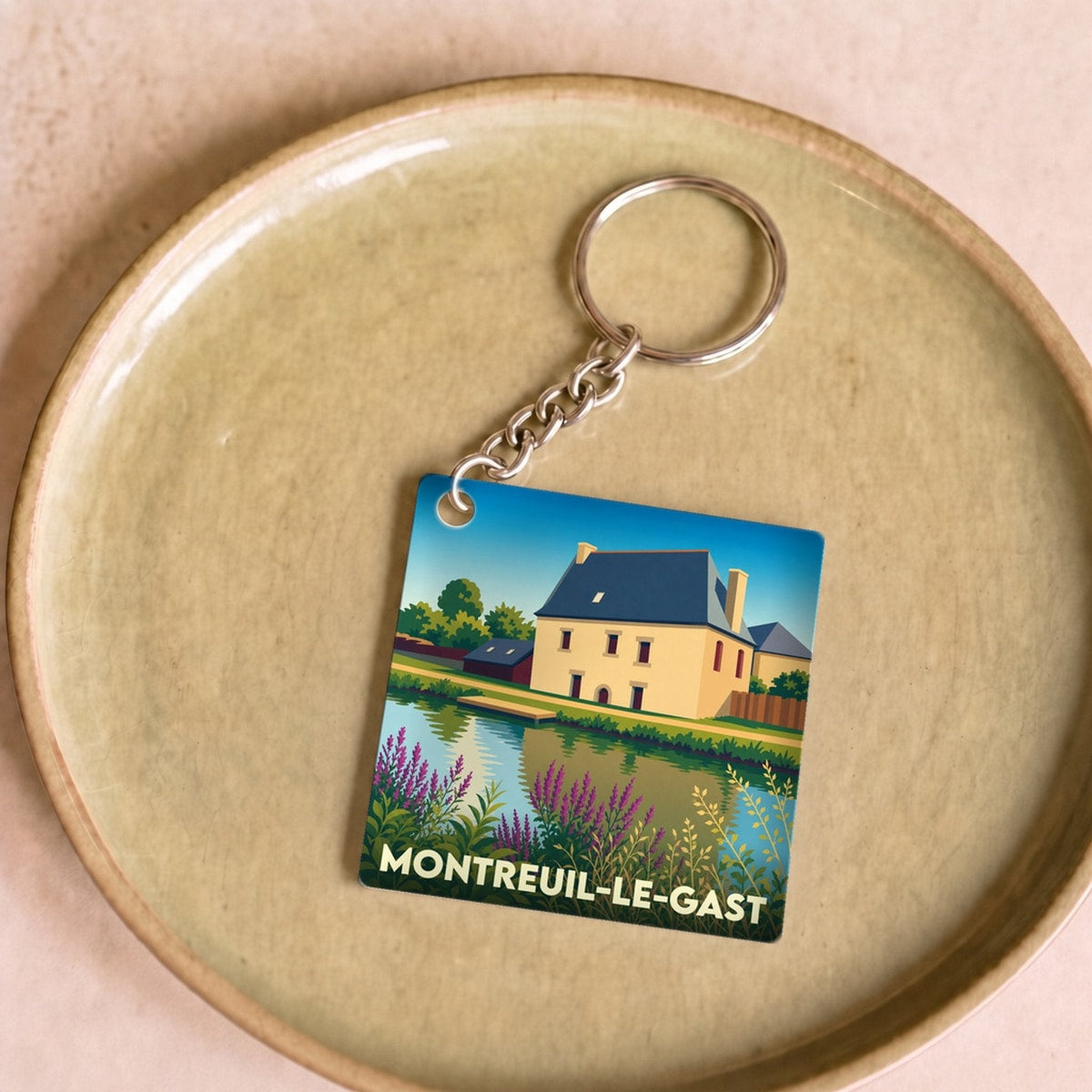 Porte-clés souvenir de la ville de Montreuil-le-Gast avec une illustration stylisée.