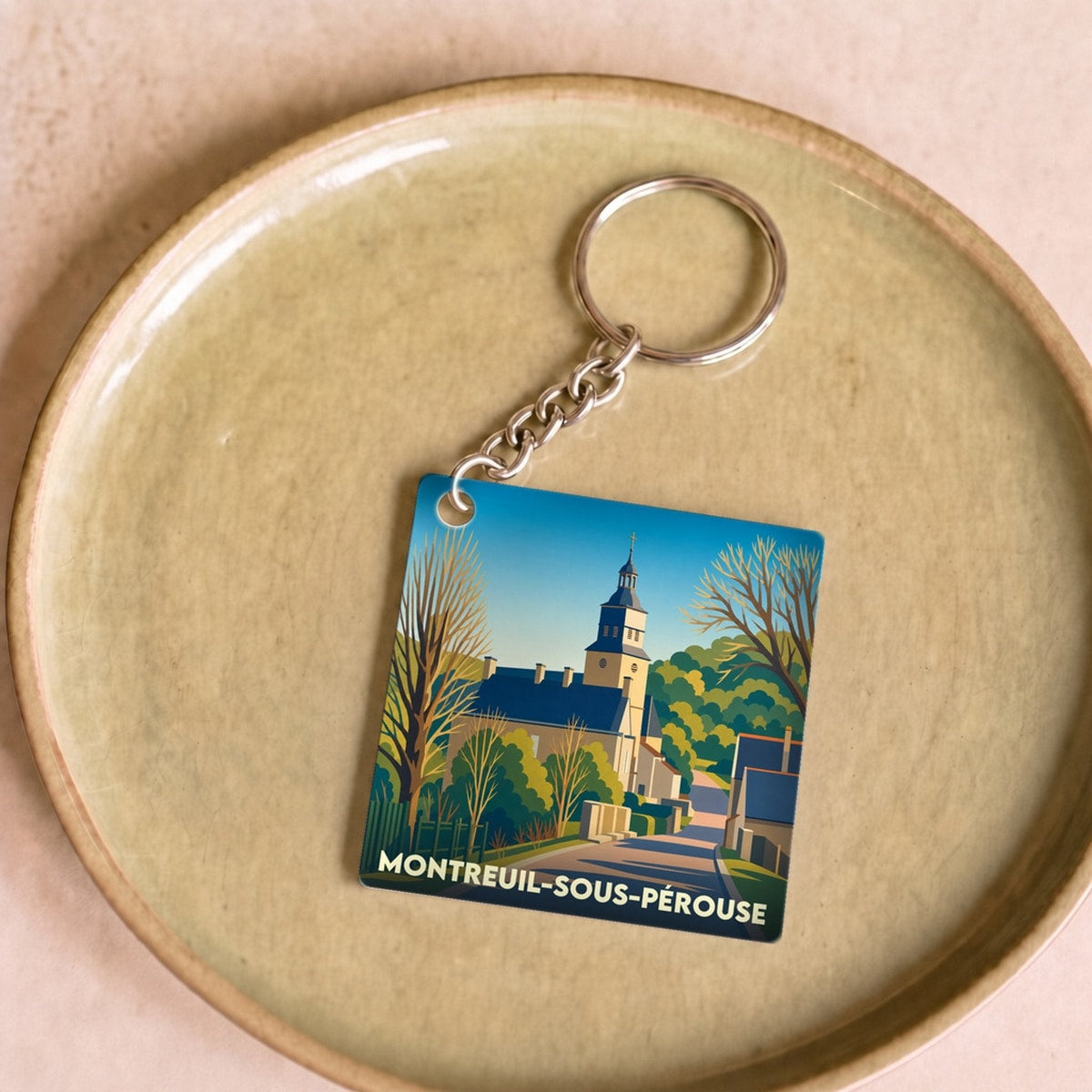 Porte-clés souvenir de la ville de Montreuil-sous-Pérouse avec une illustration stylisée.