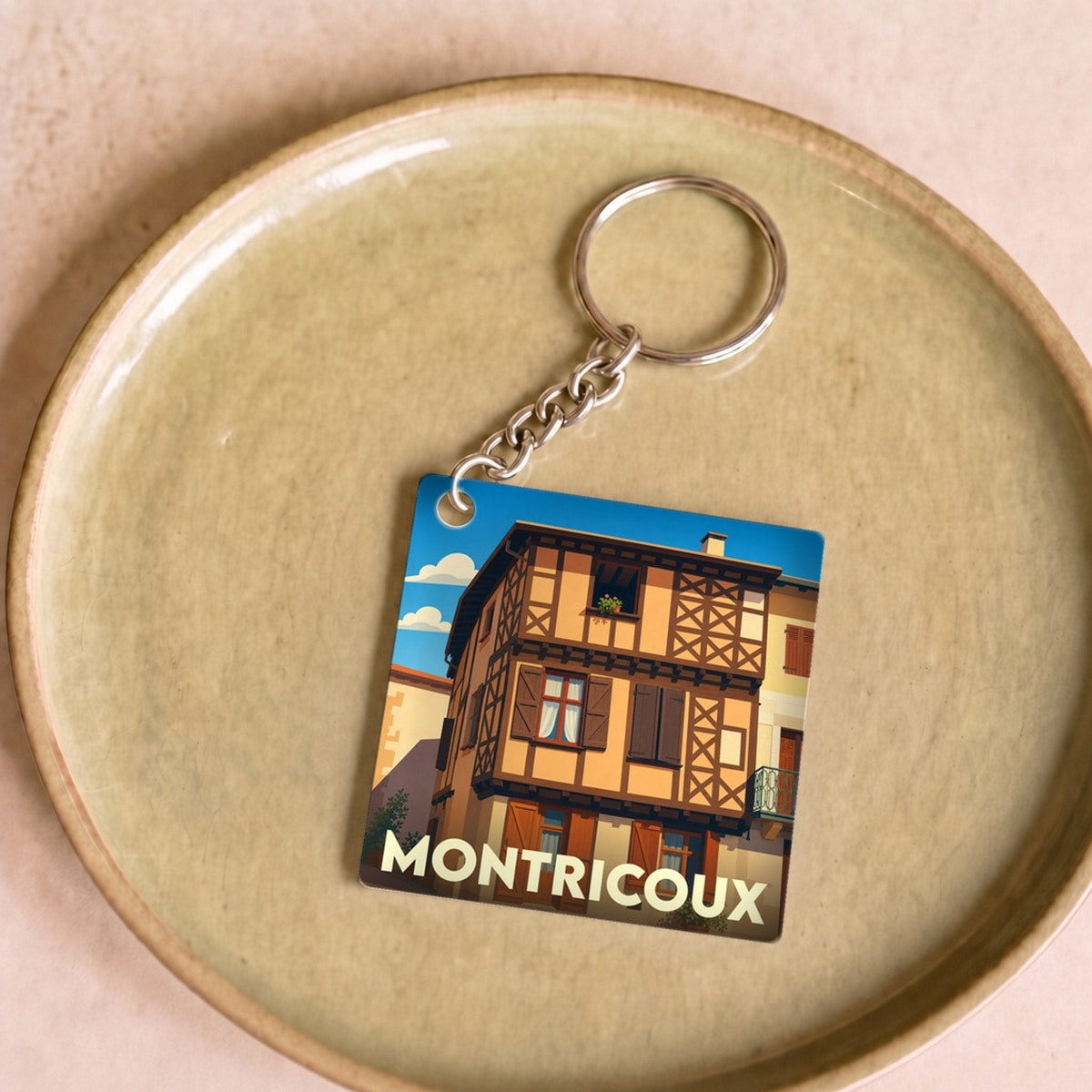 Porte-clés souvenir de la ville de Montricoux avec une illustration stylisée d'une maison à colombages.