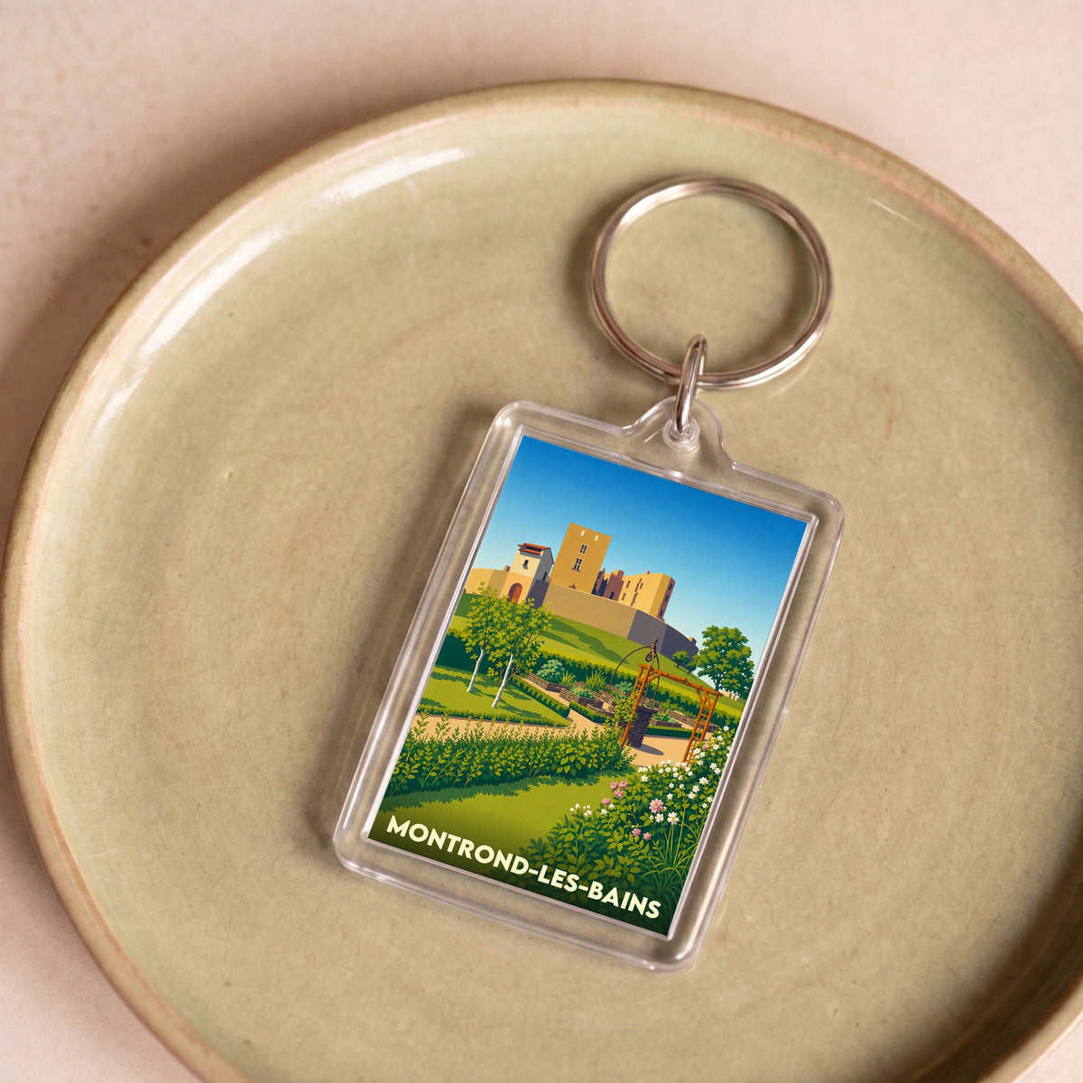 Porte-clés souvenir de la ville de Montrond-les-Bains avec une illustration stylisée de son château et de ses jardins.