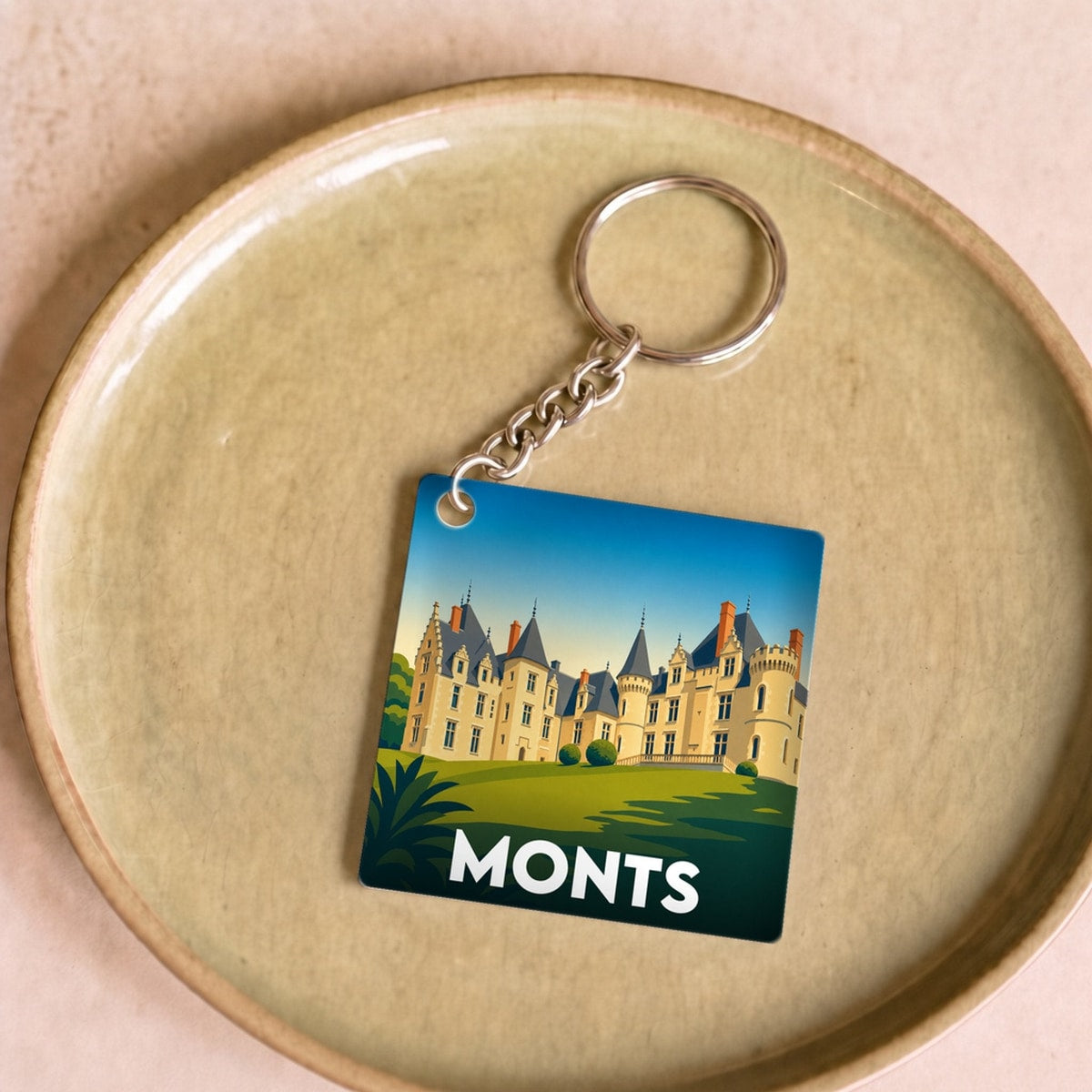 Porte-clés souvenir de la ville de Monts avec une illustration stylisée d'un château.