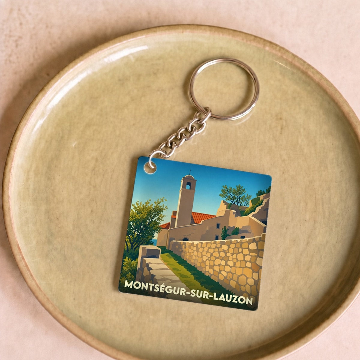 Porte-clés souvenir de la ville de Montségur-sur-Lauzon avec une illustration stylisée.