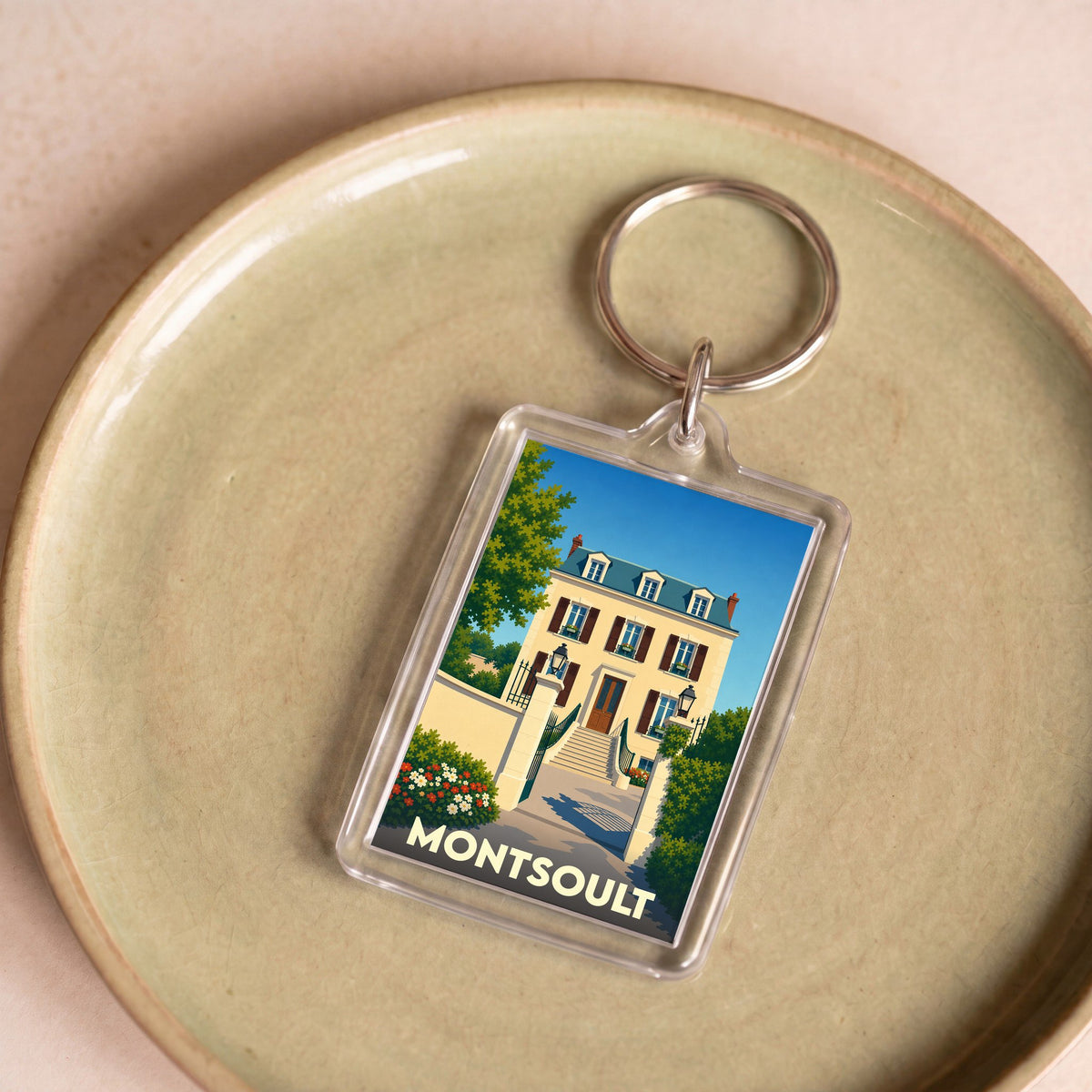 Porte-clés souvenir de la ville de Montsoult avec une illustration stylisée d'une demeure bourgeoise.