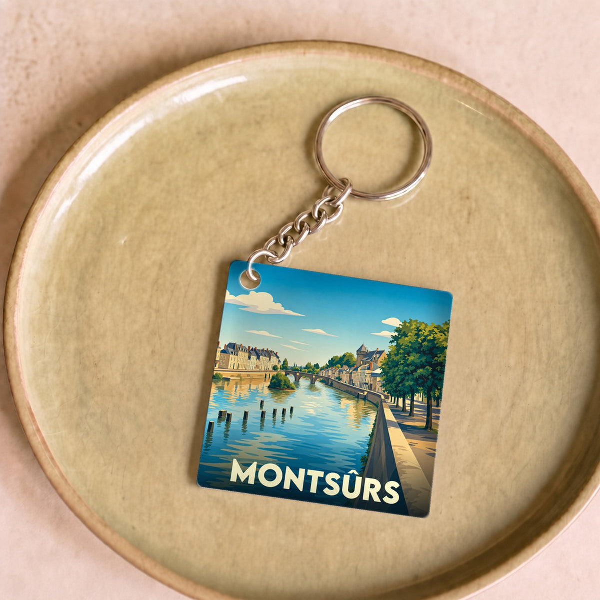 Porte-clés souvenir de la ville de Montsûrs avec une illustration stylisée.