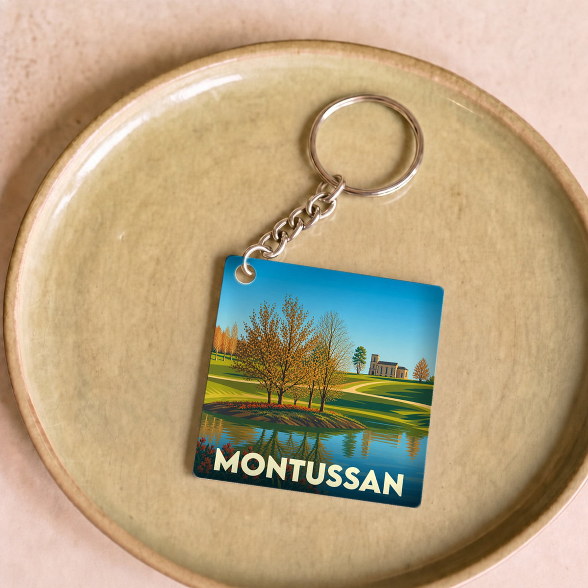 Porte-clés souvenir de la ville de Montussan avec une illustration stylisée d'un paysage naturel et calme.