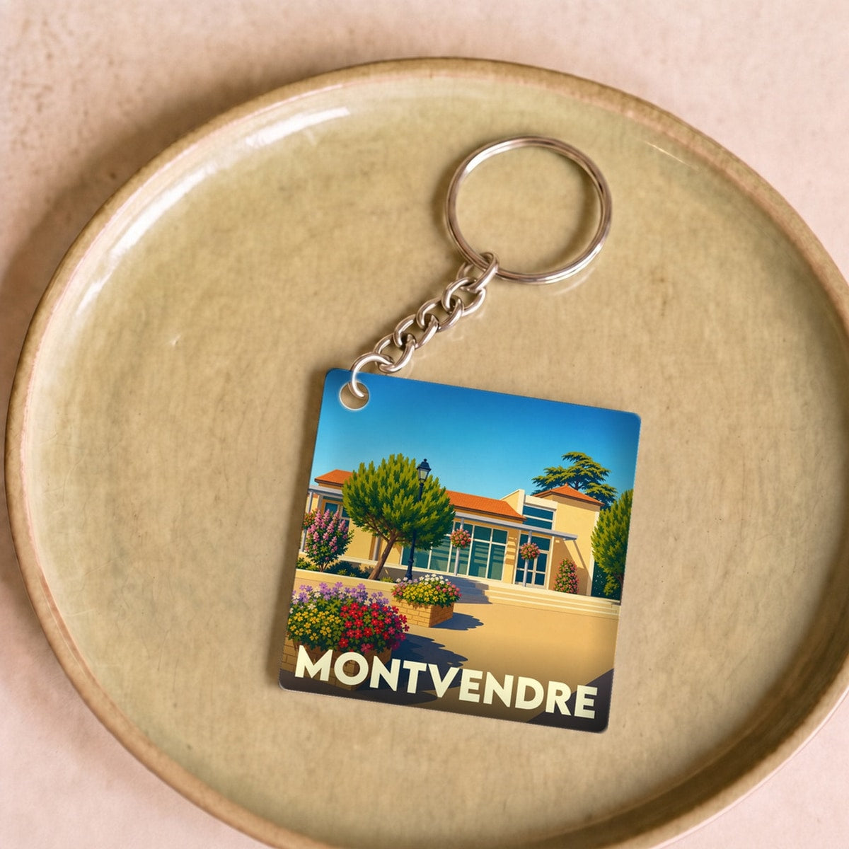 Porte-clés souvenir de la ville de Montvendre avec une illustration stylisée et colorée.