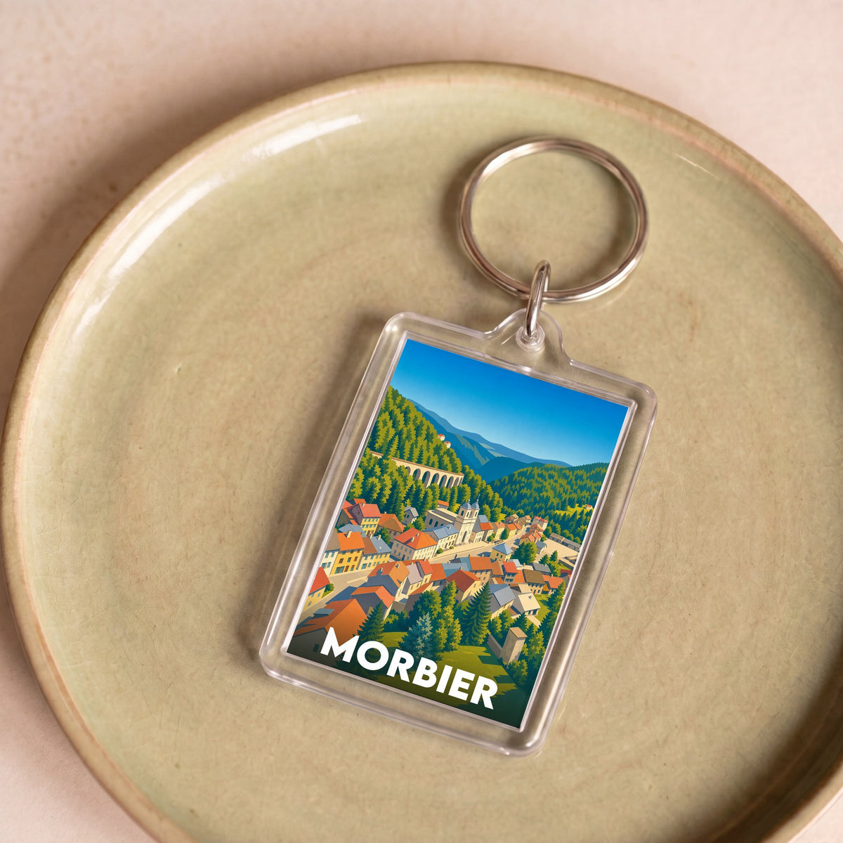 Porte-clés souvenir de la ville de Morbier avec une illustration colorée et stylisée de ses paysages.