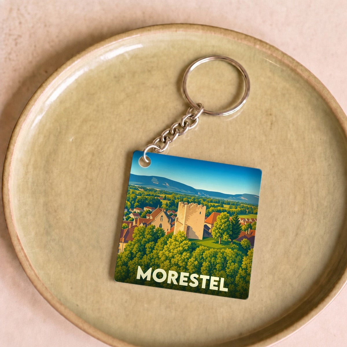 Porte-clés souvenir de la ville de Morestel avec une illustration stylisée de ses paysages et monuments.