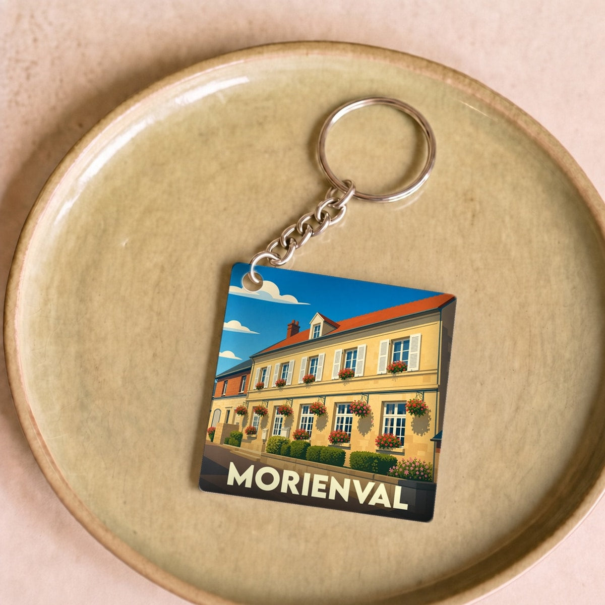 Porte-clés souvenir de la ville de Morienval avec une illustration stylisée d'une maison fleurie.