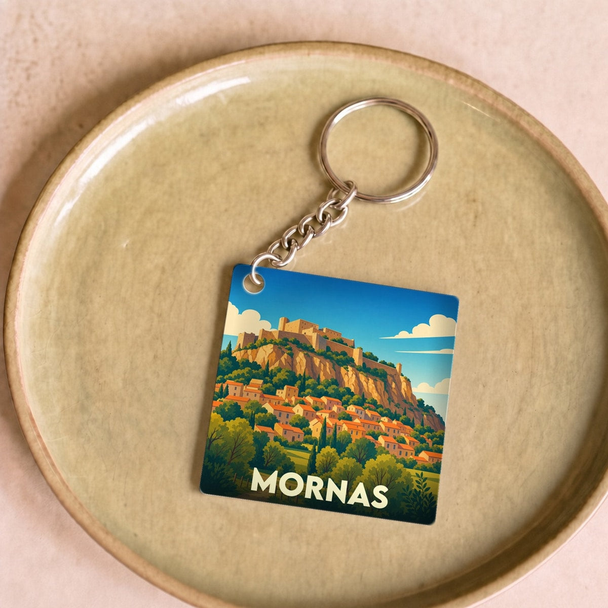Porte-clés souvenir de la ville de Mornas avec une illustration stylisée de sa forteresse et de son village.