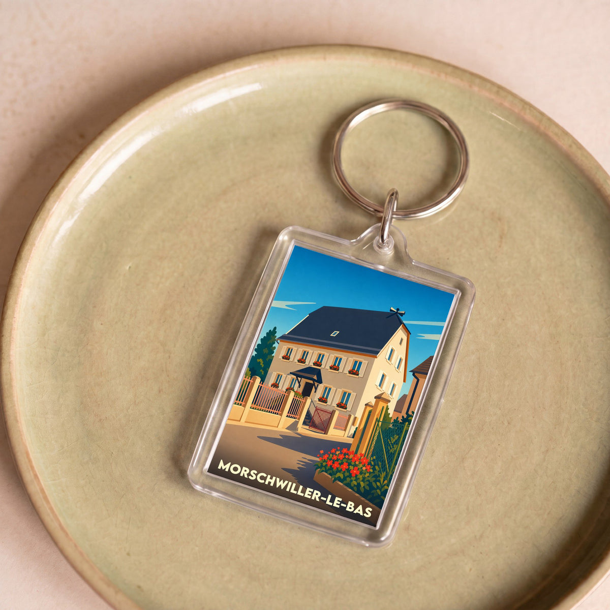 Porte-clés souvenir de la ville de Morschwiller-le-Bas avec une illustration stylisée d'une maison alsacienne.