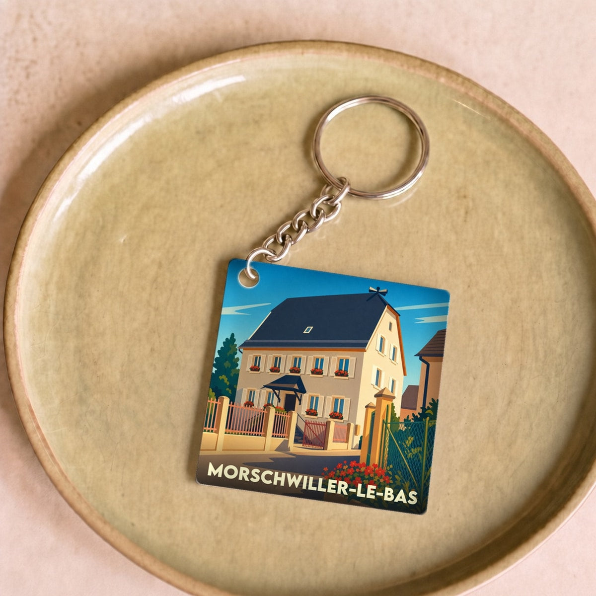 Porte-clés souvenir de la ville de Morschwiller-le-Bas avec une illustration stylisée d'une maison alsacienne.