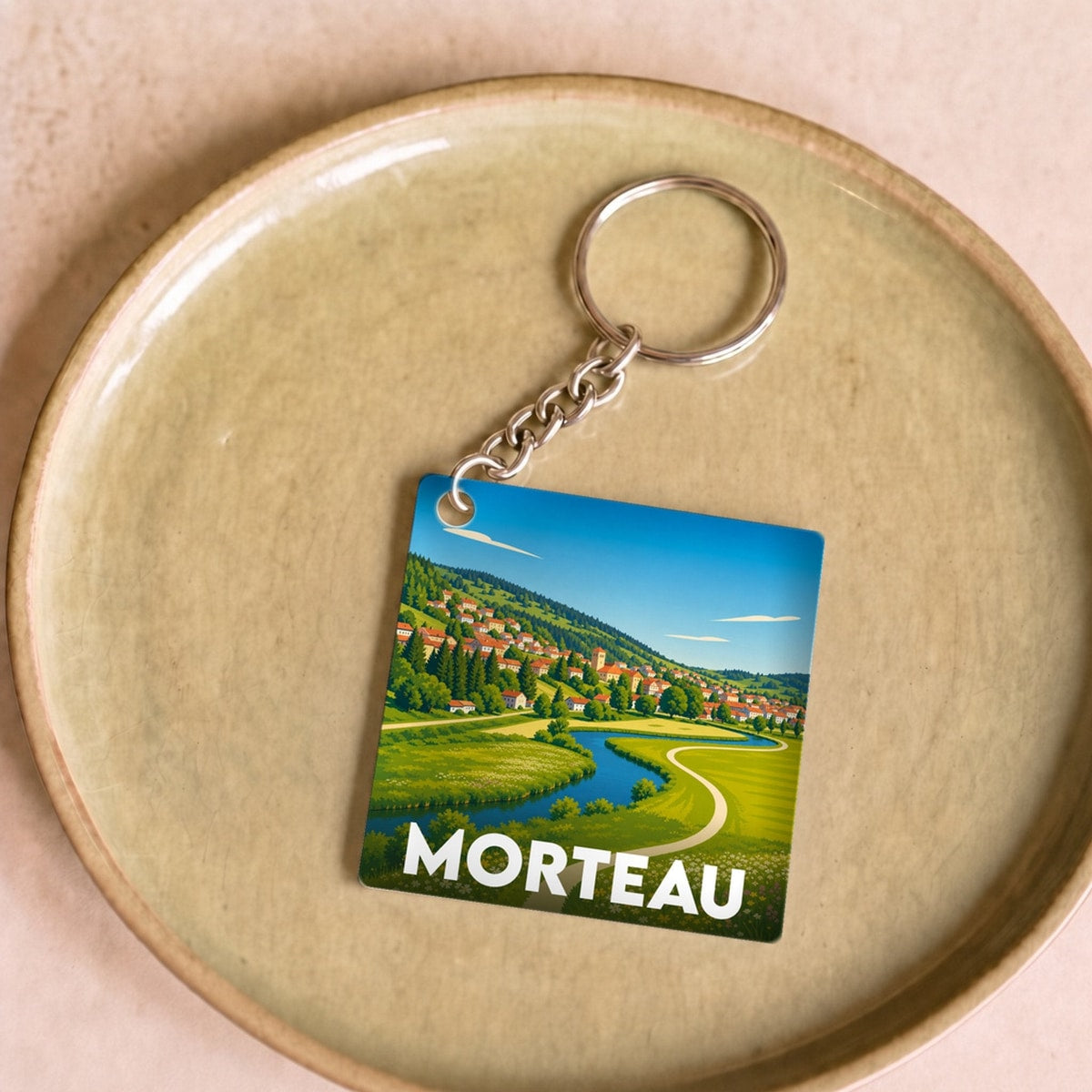 Porte-clés souvenir de la ville de Morteau avec une illustration paysagère stylisée.