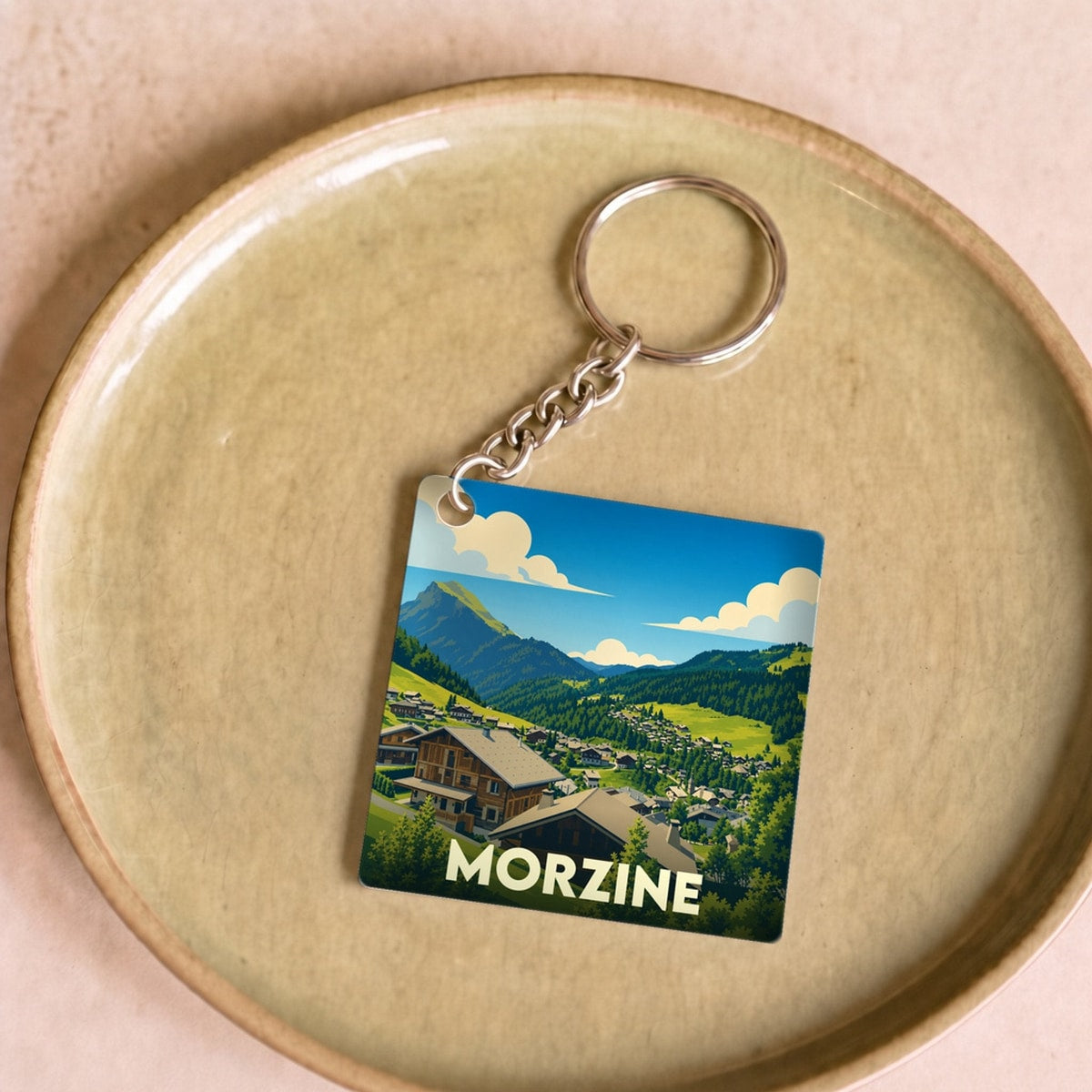 Porte-clés souvenir de la ville de Morzine avec une illustration stylisée de chalets en montagne.