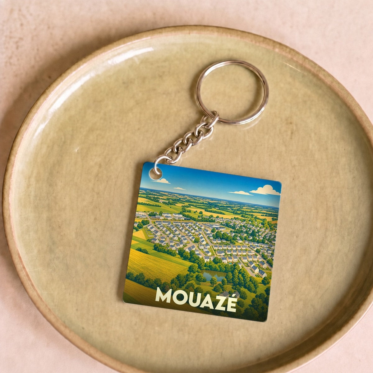 Porte-clés souvenir de la ville de Mouazé avec une illustration aérienne stylisée.